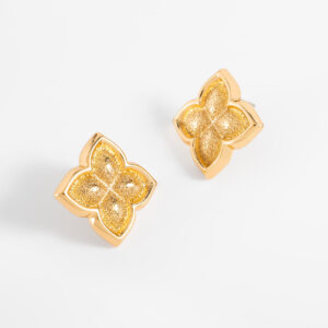 Aretes con diseño de trébol chapado en oro y textura brillante.